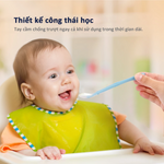 Em bé đeo yếm màu xanh lá đang được đút bằng thìa - Kèm thông tin thiết kế sản phẩm an toàn, không chứa BPA và chất liệu silicon mềm mại.